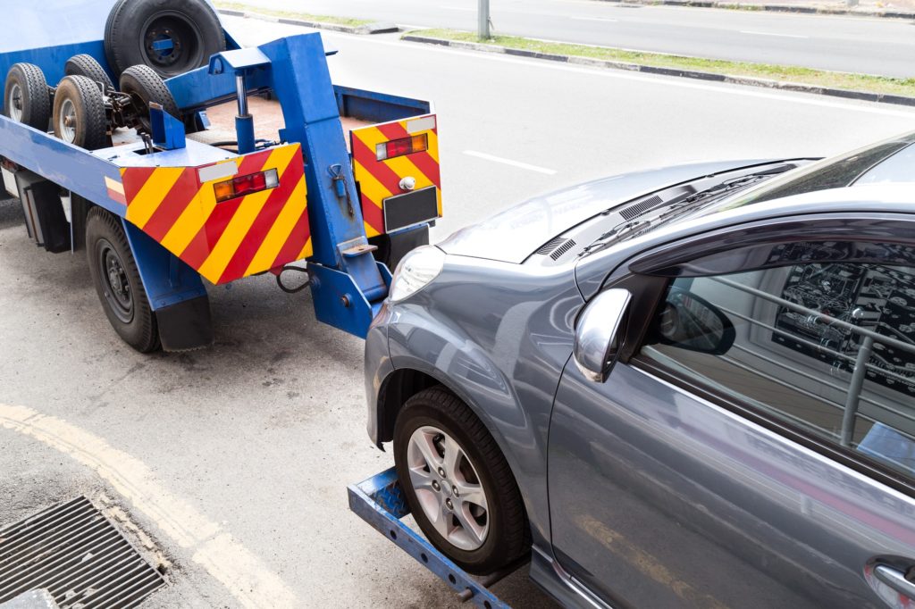 Tow truck towing a broken down car on the street